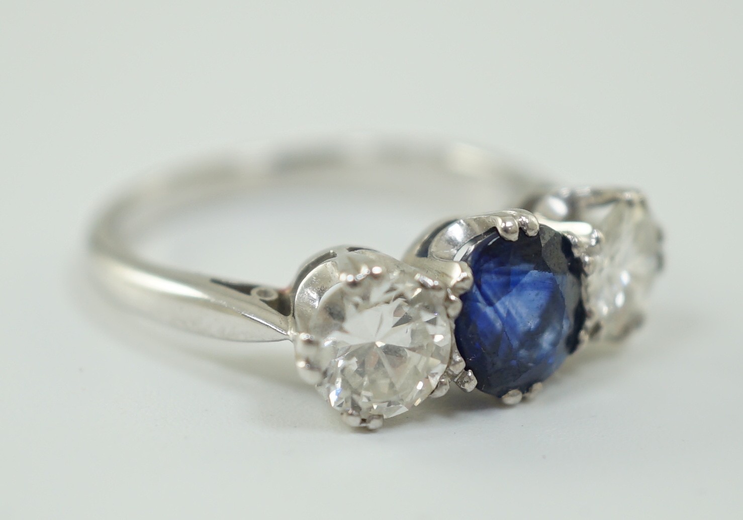 A modern 18ct white gold, single stone oval cut sapphire and two stone round cut diamond set ring